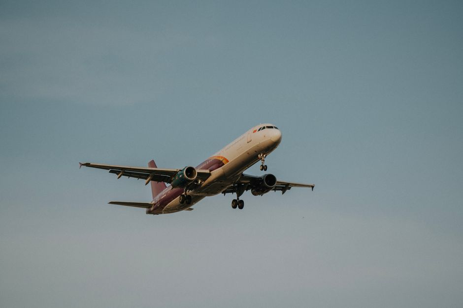 A commercial airplane flying against a clear blue sky, showcasing travel and aviation.
