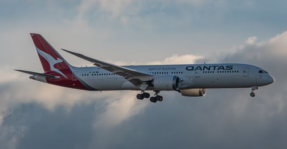 Elegant capture of a Qantas Dreamliner ascending into a cloudy sky, showcasing modern aviation.