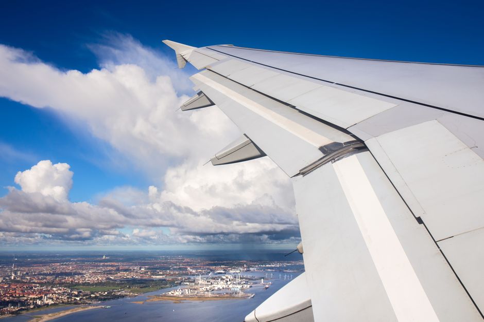 View of city and clouds from an airplane window, showcasing urban landscape and sky.