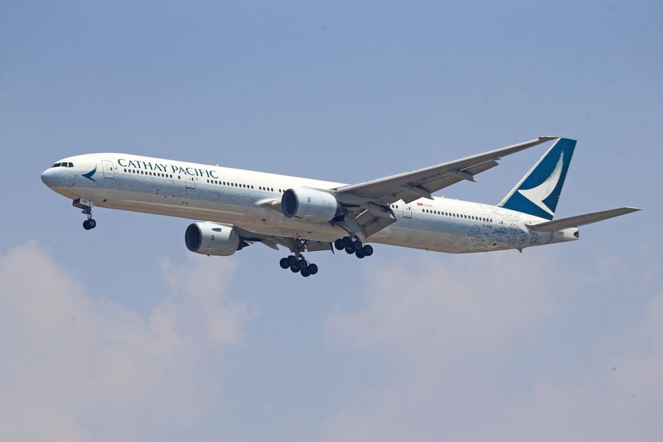 A Cathay Pacific aircraft captured mid-flight, soaring through clear skies.