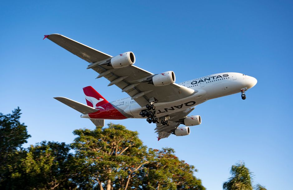 A Qantas Airbus A380 flying low over Los Angeles with landing gear extended.