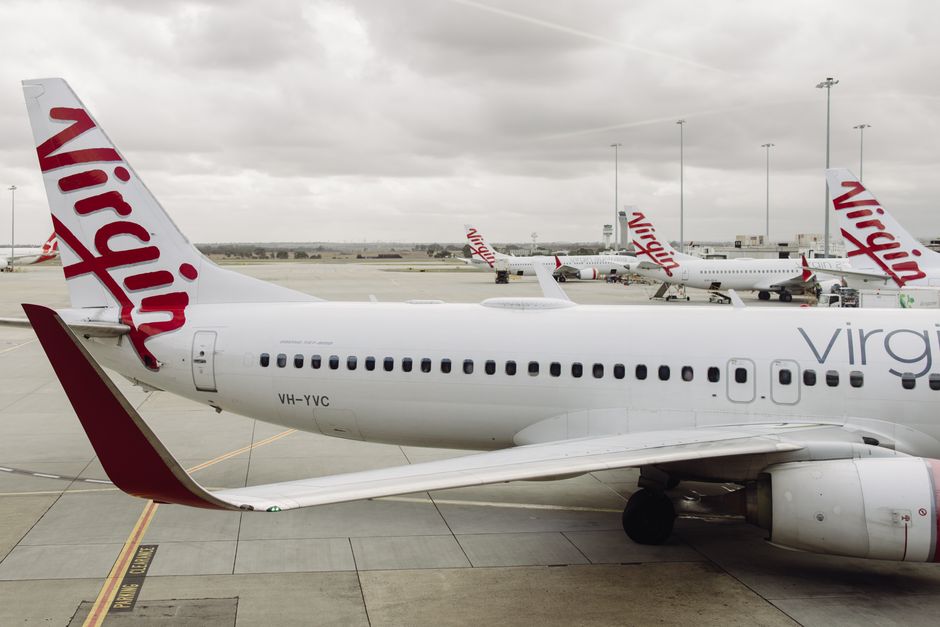 Virgin Australia Boeing 737 aircraft parked at Melbourne Airport under cloudy skies.
