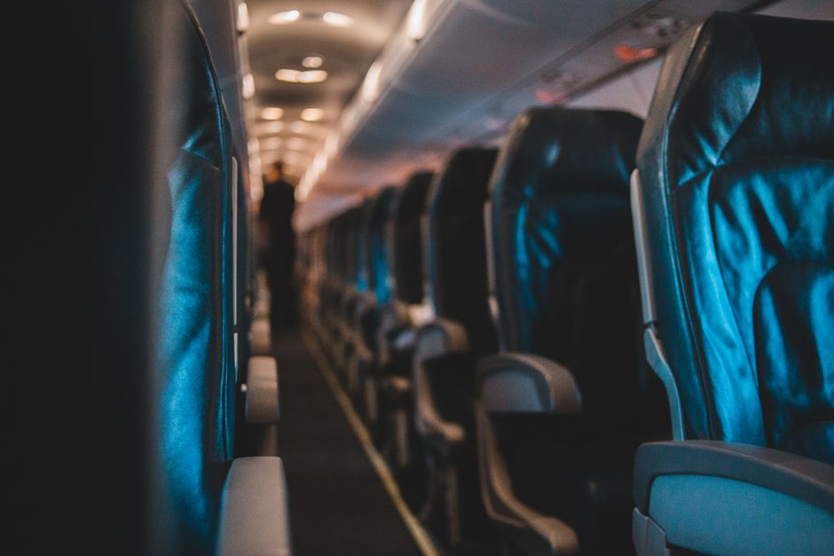 Interior view of an empty airplane cabin with leather seats and soft lighting.