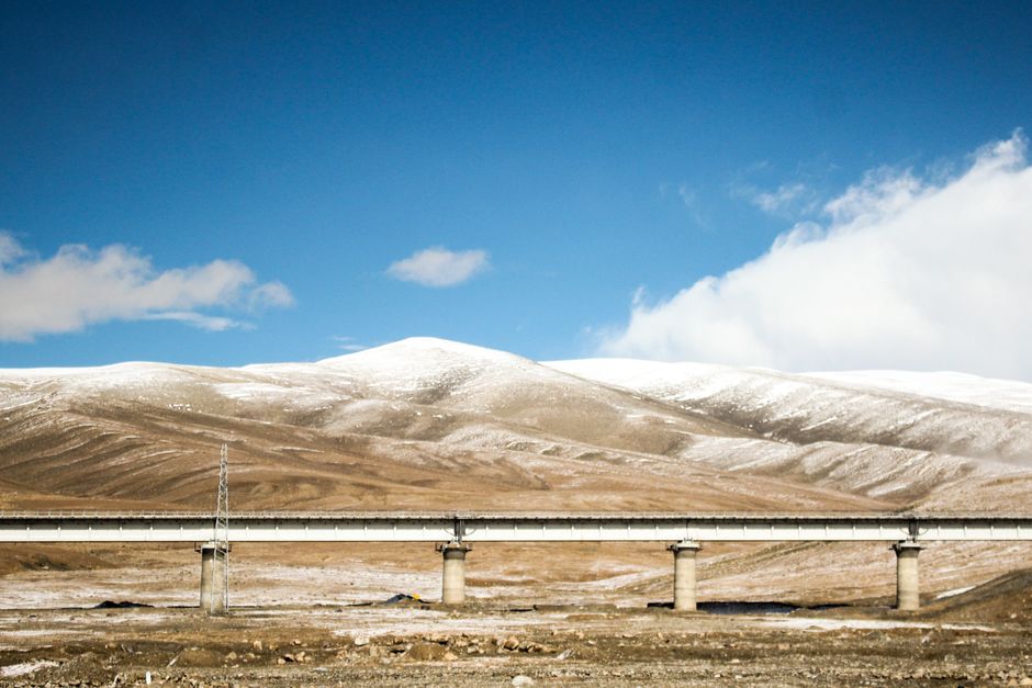 A serene winter mountain landscape with a bridge under a blue sky, ideal for nature and travel themes.