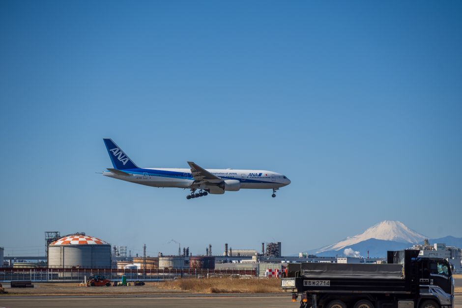 Airplane approaching runway with Mount Fuji in the background, showcasing travel and aviation.