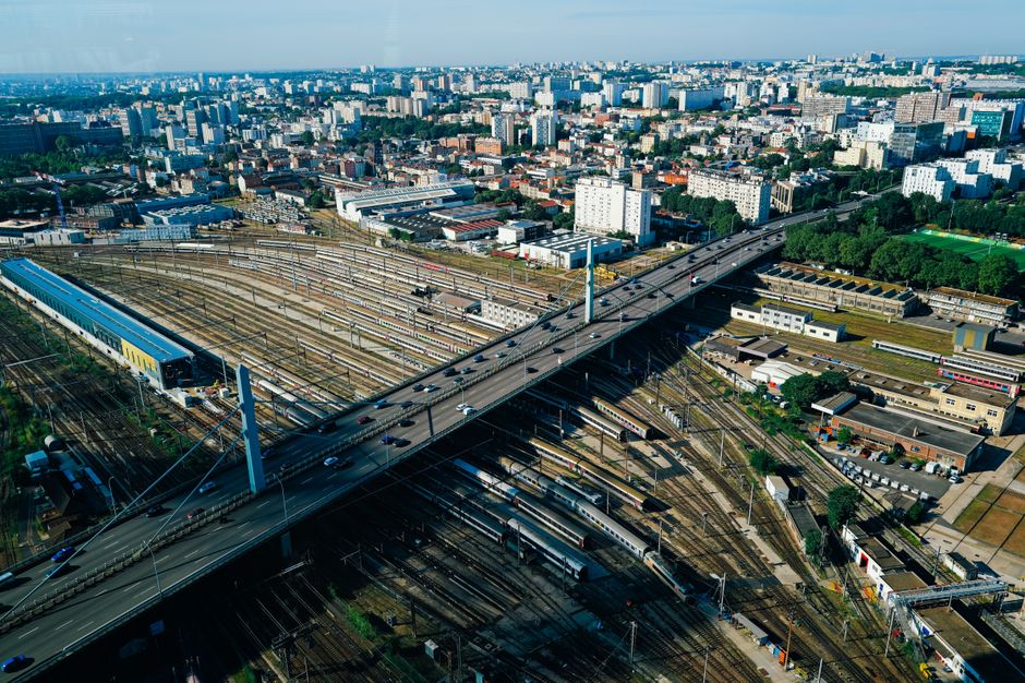 Stunning aerial cityscape featuring a highway over bustling railways and sprawling urban buildings.