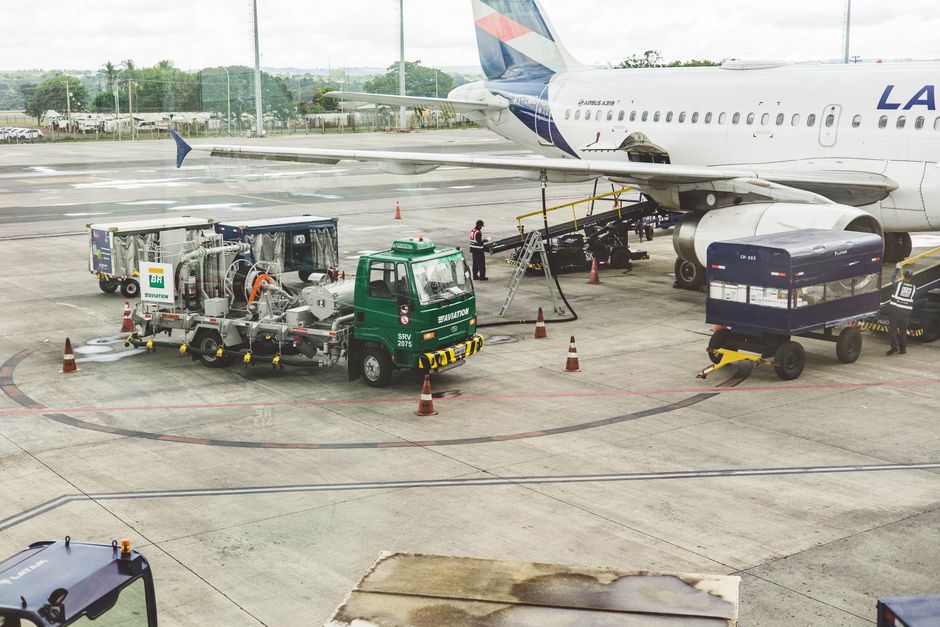 Ground support services in action at an airport terminal with visible aircraft and service vehicles.